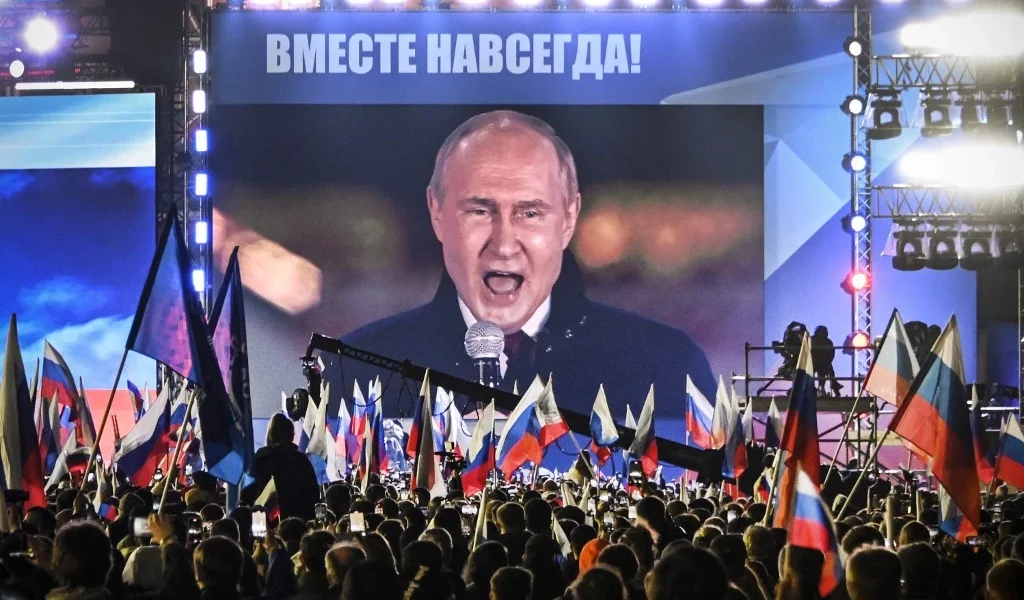 Vladimir Putin speaking at a campaign rally, showcasing his leadership bid for Russia's presidency.