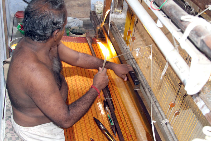 Hands of a skilled weaver working on a traditional handloom, creating a Kanchipuram silk saree with fine mulberry silk threads and vibrant colors.