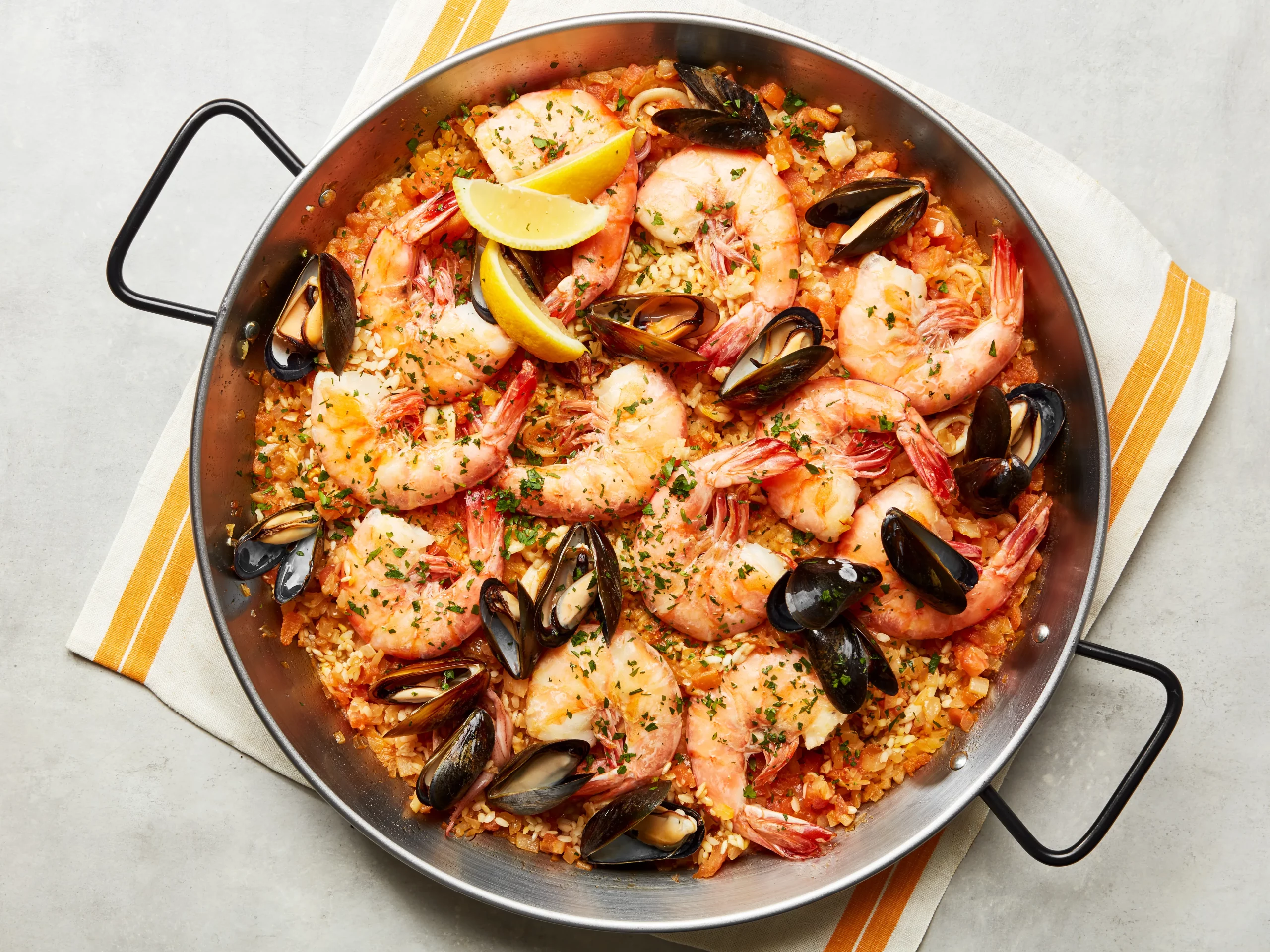 Plated seafood paella garnished with lemon wedges and fresh herbs, ready to be served and enjoyed with a glass of wine.