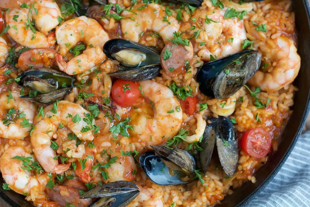 Traditional seafood paella served in a shallow pan, showcasing vibrant colors and enticing textures.